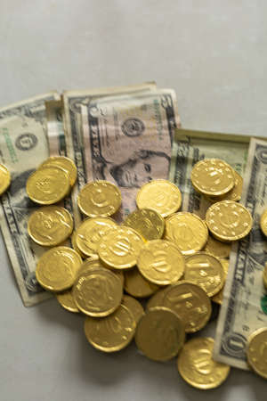 golden chocolate coins placed on real dollar money with selective focus concept buy saleの写真素材