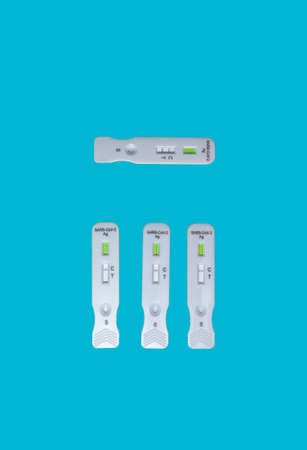 Close-up of several antigen tests for Covid19 with negative and one positive result on a blue backgroundの写真素材
