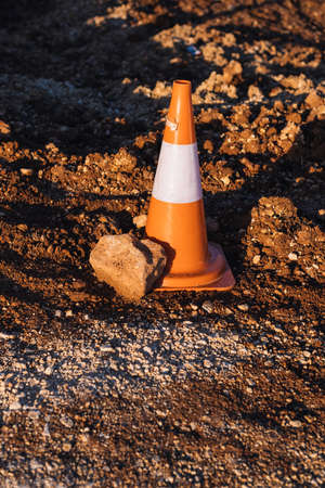 detail of an orange construction site cone with a stone to indicate a safetyの写真素材