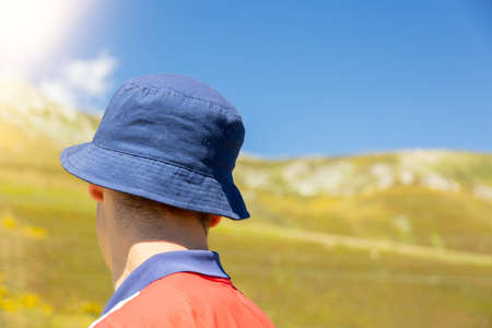 detail of a boy on his back with blue cap in the bush to protect himself from the sun with copy space concept of solitudeの写真素材