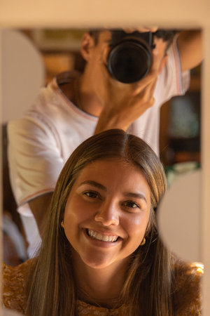 boy photographer taking pictures of his smiling girlfriend through a mirror