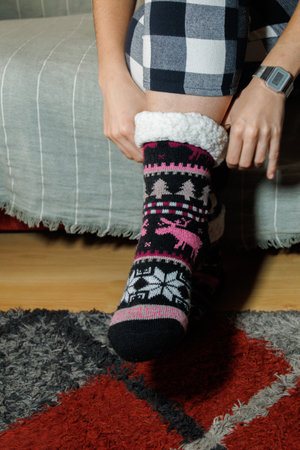girl putting on a pair of warm wool socks with Christmas patterns to enjoy peace and quiet at homeの写真素材