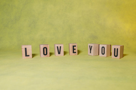word LOVE YOU constructed by wooden letters on yellow background with copy space to give a message advertising conceptの写真素材