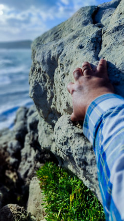 detail of a hand clinging to a rock on a cliffの写真素材