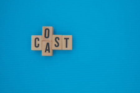 Wooden blocks with the words COST and CAST forming a cross on a bright minimalist blue background.の写真素材