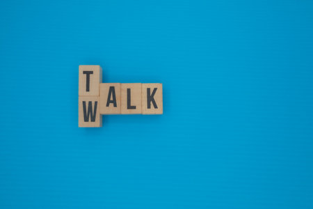 Title: Words WALK and TALK formed with wooden blocks on vibrant blue backgroundの写真素材