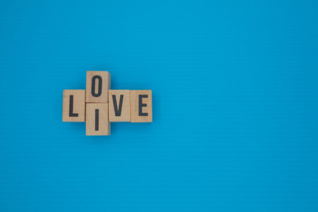 Wooden cubes with words LIVE and LOVE on vibrant blue background