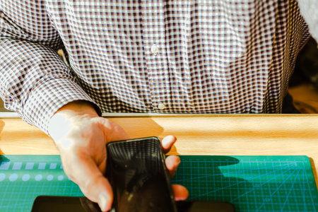 Man holding smartphone over green cutting mat