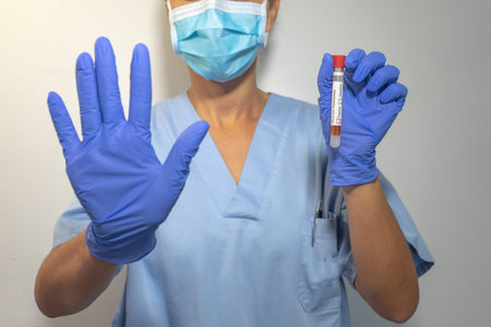 Nurse gestures to stop coronavirus. With one hand it indicates to stop and in the other hand it...