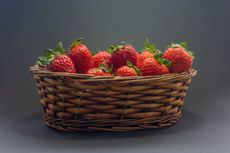 Basket with strawberries. The background is a dark color. Strawberries is a fruit that can be eaten in different ways.の写真素材
