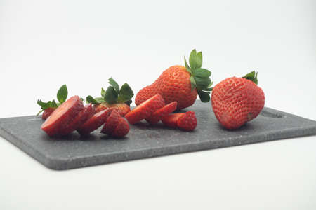 Strawberries cut into small pieces on a cutting board.の写真素材
