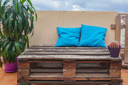 Balcony of a house. There is a wooden pallet, a plant, a cactus and cushions.の写真素材