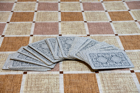 Deck of cards spread out on a table with a checkered tablecloth.