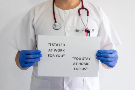 Close-up of a male nurse holding a sign. The sign says I stayed at work for you. The nurse has a...