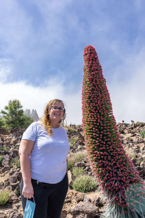 Young tourist woman observing a Tajinaste in bloom. This flora can only be observed in the Teide National Park, in Tenerife.の写真素材