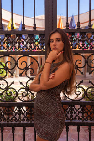 Woman with arms crossed. She wears a short dress. In the background there is a door with iron bars. It is located in Las Americas, Tenerifeの写真素材