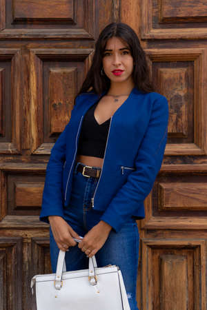 Young woman posing with a white handbag. In the background you can see an old wooden door. The photo was taken in La Laguna, Tenerife.の写真素材
