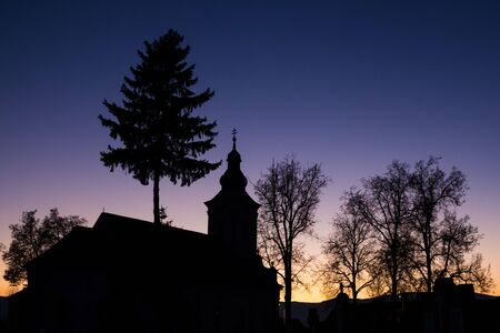 Silhouette of a small church and some trees in the evening, with deep blue sky.の写真素材