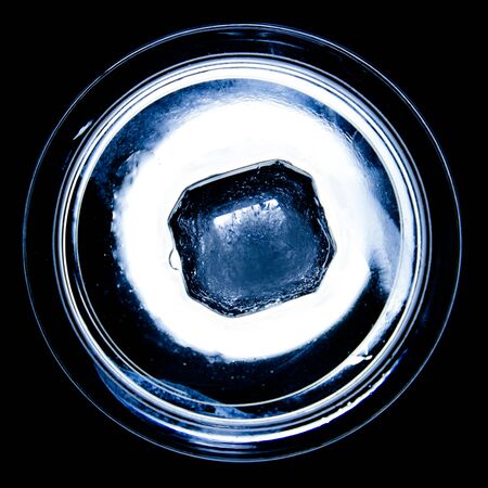 Ice cube in a circle shaped saucer from a high angle, backlit.の写真素材