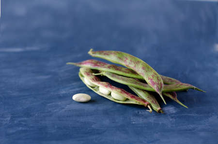 Pods of green beans close-up lie on a blue background. Copy space, place for textの写真素材