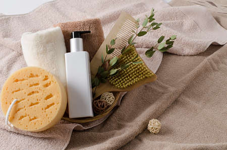 A set of ecological natural accessories for body, face, hands care. Cream, washcloth, wooden comb, wooden massage brush, cotton towels lie on pastel brown towels with copy space.の写真素材