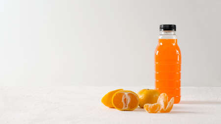 Tangerine drink in bottle on light background with tangerines, copy space and selective focusの写真素材
