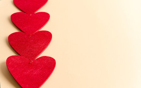 Red hearts close up lie on beige background, valentine background concept with copy space and flat layの写真素材