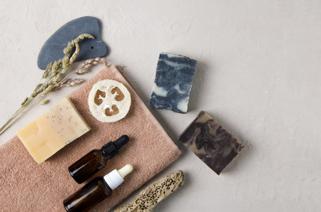 Cosmetic accessories for body, hand, face care. On the towel lies natural soap, natural serum in glass bottles with a pipette, natural stone guache, a washcloth. Natural cosmetics concept flat lay, copy spaceの写真素材