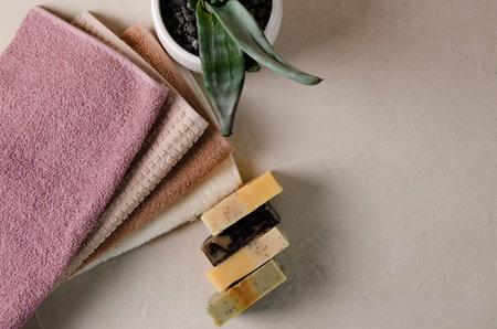 Lump soap made from natural ingredients and a stack of clean cotton hand towels lie on a beige...