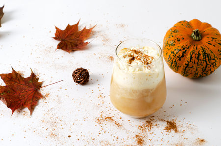 Spicy pumpkin latte in a glass with cream and cinnamon. Concept of autumn warm drink with pumpkins...