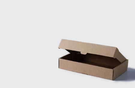 Open box made of brown cardboard on a light background. Empty box for packaging and delivery of goods low with copy spaceの写真素材