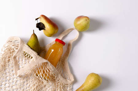 Pears of the Trout variety and conference with eco-sumka, a small one on a white background. There is a glass bottle with fruit juice in the eco-sup. copying space, flat layoutの写真素材