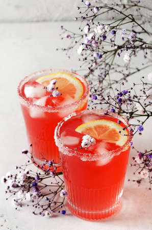 Cold grapefruit cocktail with ice and flowers in a glass glassの写真素材