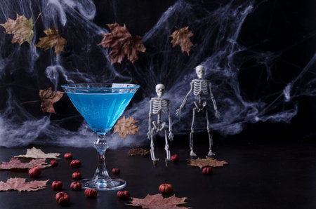 Halloween cocktail. Festive drink. Halloween party. Pumpkins, spider webs, skeletons on a dark toned...