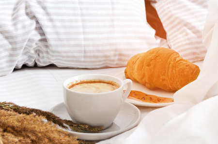 A cup of coffee with croissants in bed. The concept of morning coffee in bed.の写真素材