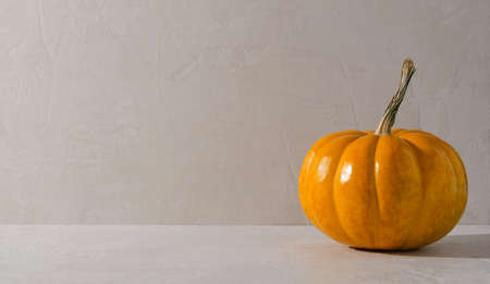 Minimalism autumn background - orange pumpkin on a beige background. Empty background for demonstration of drinks, food, products with copying of text.の写真素材