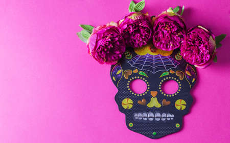 Black carnival mask holiday dia de Muertos on pink background with flowers, copying text, flat layout, minimalismの写真素材