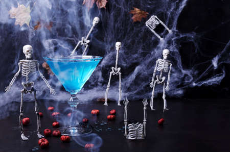Halloween is a festive drink on a black background with skeletons, cobwebs, mini pumpkins and smoke. Selective focusの写真素材