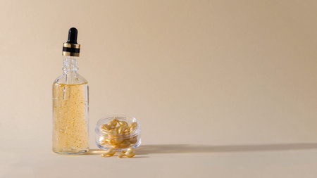Gel serum in a glass bottle with a pipette and capsules with serum for skin care of the face, eyes, body in a container on a beige background. Demonstration of cosmetic product for skin careの写真素材