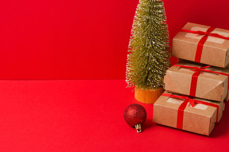 A bunch of Christmas gifts made of kraft cardboard with red ribbon, Eco tree on a red background....