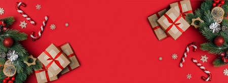 Christmas. Festive background, banner, gifts in kraft packaging with branches of the tree, Christmas canes on a red background.の写真素材