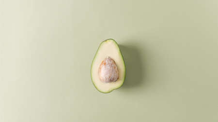 Herbal background for demonstration of cosmetic products. Cut avocado with walnut on a green pastel backgroundの写真素材