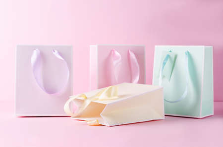 The concept of in-store shopping. Gift paper bags in pastel colors on a pink background, selective focusの写真素材
