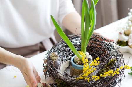 Women's hands hold an Easter decorative wreath on the table. Easter background with selective soft...