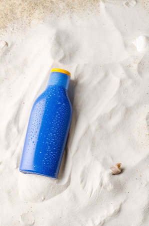 sun protection. Cream, tanning lotion, anti-tanning. Blue plastic bottle on sand, vertical...
