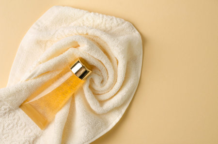 Gel, serum, liquid soap, lotion with gold additives on a towel and brown background with selective...