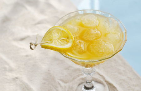 A cold, summer refreshing drink in a close-up glass. Wine glass stands on the sand, hard shadows,...