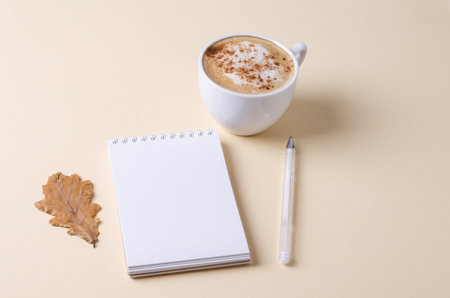 autumn background. Empty white notepad with a cup of coffee in a white porcelain cup on a light...