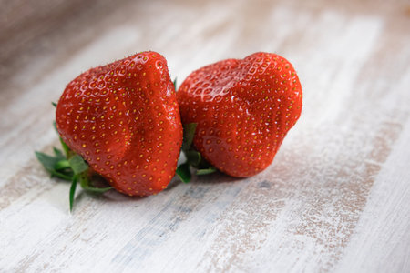 Two ripe juicy strawberries on a wooden tableの写真素材