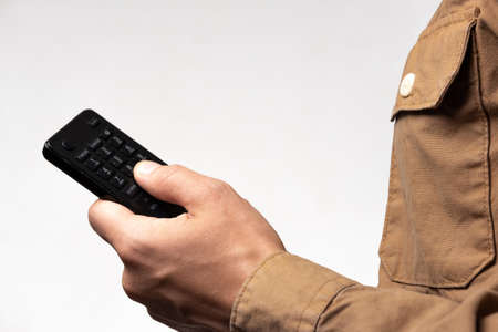 Male hand with a TV remote control on a white backgroundの写真素材